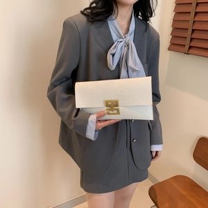 Pochette enveloppe blanche motif crocodile avec boucle dorée dans un décor lifestyle