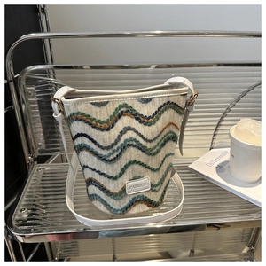 Close-up of knit bucket bag with colorful wave patterns and white leather shoulder strap