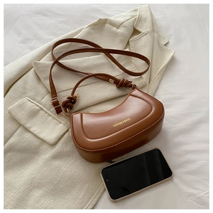Close-up of brown crescent handbag with knotted handle and golden brand lettering