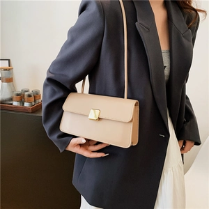 Borsa a tracolla beige minimalista con fibbia dorata indossata da una modella urban