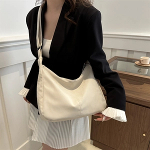 Minimalist cream crescent crossbody bag with decorative stitching and adjustable strap