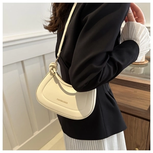 Chic beige half-moon shoulder bag with tied strap detail shown in casual lifestyle setting