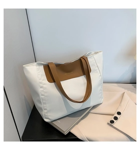 Detail of white PU leather tote bag with brown handles and fashion logo patch