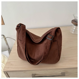 Detail of brown corduroy tote bag showing textured fabric and adjustable strap buckle