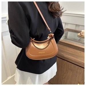 Close-up of brown crescent bag with knot handle detail and textured PU leather finish