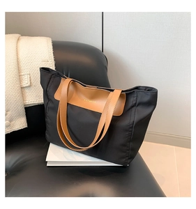 Close-up of black nylon tote bag with brown leather accents and FASHION lettering