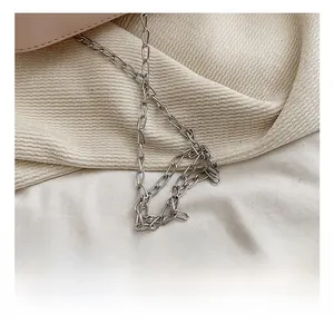 Detail of elegant silver metal chain strap on minimalist beige textured handbag fabric