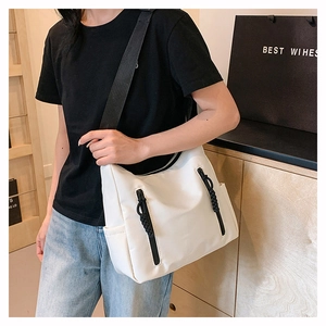 Close-up of white nylon crossbody bag featuring dual black zippers and wide shoulder strap