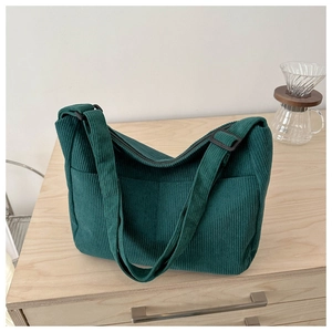 Detail of dark green corduroy tote bag showing thick ribbed fabric and outer pocket