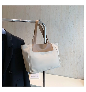 Detail of the high-capacity cream tote bag with brown straps and gold Fashion logo