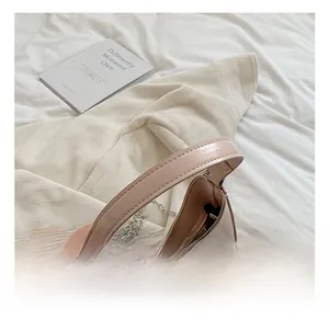 Detail of silver bow clasp on pink patent leather handbag with a metallic chain strap