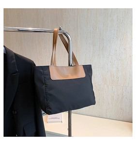 Detail of gold logo on black nylon tote bag with premium brown faux leather handles