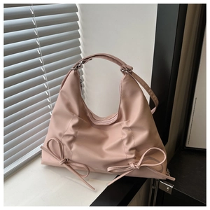 Dettaglio di una borsa tote rosa chiaro con fiocchi e manico superiore elegante