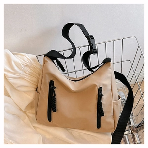 Detail view of khaki nylon crossbody bag featuring front double vertical zipper pockets