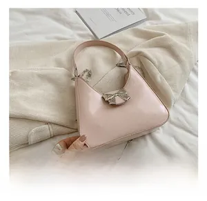 Detailed close-up of pink patent hobo bag with silver bow accent and chain strap