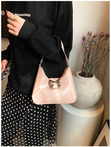 Close-up of pink patent leather bag with a golden metal bow and elegant chain strap