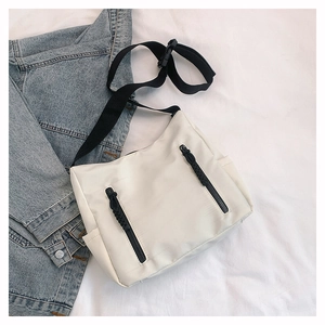 Detail view of ivory nylon crossbody bag with dual vertical black zipper pockets