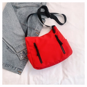 Detail of red nylon crossbody bag with dual vertical zippers and wide adjustable strap