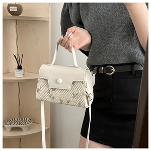 Détail d'un petit sac carré blanc tressé avec poignée élégante et fermoir métallique