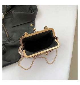 Detail view of vintage kiss-lock bag showing embroidery and golden chain strap