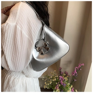 Detailed close-up of a silver metallic bow buckle on a textured Y2K style shoulder bag