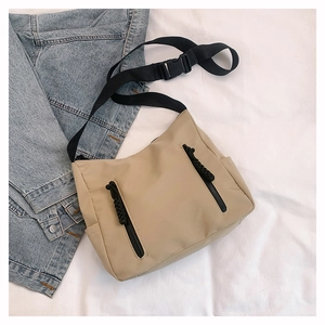 Detail of khaki nylon crossbody bag with dual vertical zippers and wide black strap
