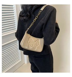 Sac baguette beige à motif papillon et chaîne dorée porté par un mannequin de dos