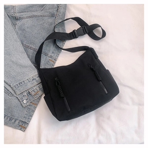 Detail of black nylon crossbody bag with adjustable strap and dual vertical zipper pockets
