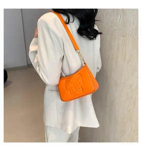 Détail du sac à bandoulière orange avec motif papillon en relief et fini brillant