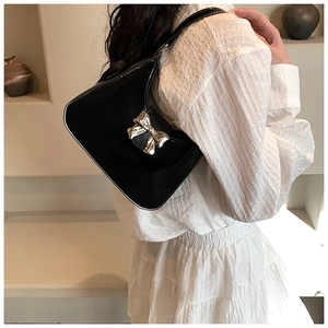Close-up of a black leather hobo bag featuring a decorative golden bow metal buckle