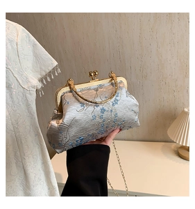 Detail of silver silk evening bag with blue floral embroidery and golden metal clasp