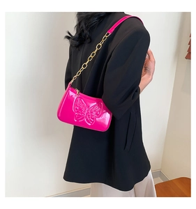 Gros plan du sac à bandoulière rose vif avec gaufrage papillon et chaîne dorée