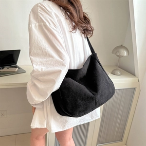 Minimalist black corduroy tote bag shown on shoulder in a casual lifestyle setting