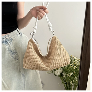 Detailed shot of straw woven shoulder bag with white rope straps and knot details