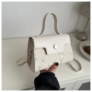 Détail du sac en paille tissée avec broderie florale verte et poignée beige chic