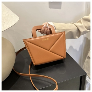 Detail of caramel faux leather bag with geometric embossed pattern and fashion logo