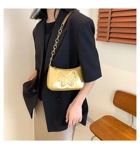 Détail du sac doré effet miroir avec un grand motif papillon en relief et chaîne