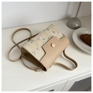 Gros plan d'un sac à main en paille avec broderies florales et détail de bandoulière