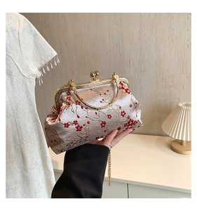 Detail of vintage champagne silk handbag with red plum embroidery and golden metal handle