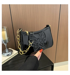 Détail du sac en cuir verni noir avec gaufrage papillon et chaîne dorée brillante