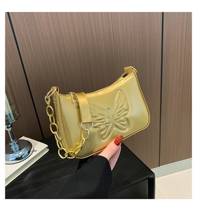 Gros plan sur le motif papillon embossé du sac à bandoulière doré à chaîne épaisse