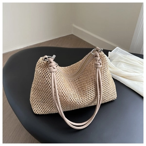 Nahaufnahme der beigen Strohtasche mit Knotengriffen und silbernen Metallringen