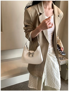 Close-up of white leather handbag with silver metal bow detail and fine chain strap