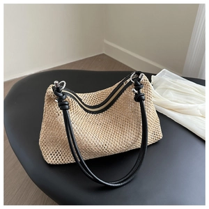 Detail der gewebten Strohtasche mit schwarzen Ledergriffen und geknoteten Akzenten