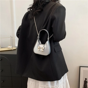 Chic silver bow metal mini shoulder bag with chain strap shown on a model in urban setting