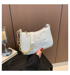 Détail d'un sac à main blanc en cuir synthétique avec papillon embossé et chaîne dorée