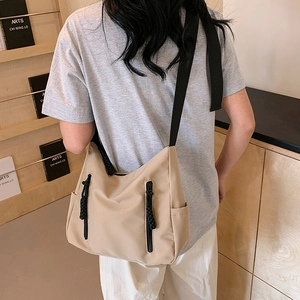 Large beige nylon crossbody tote bag for women with decorative zippers and black straps
