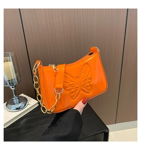 Détail du sac en cuir verni orange brillant avec papillon gaufré et chaîne dorée