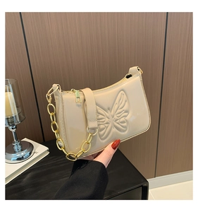 Détail du sac laqué beige avec gaufrage papillon et grosse chaîne dorée
