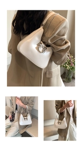 Close-up of white crescent hobo bag with metallic bow detail and silver chain strap